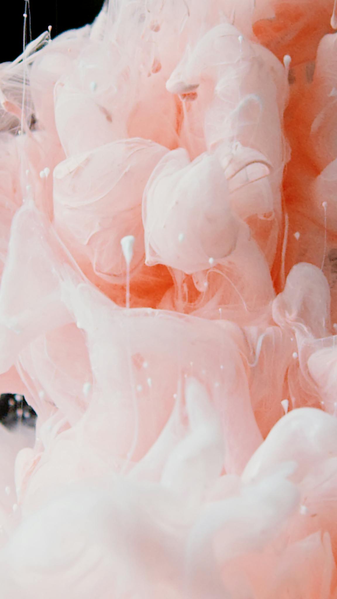 Abstract pink and white paint splatter creating an artistic pattern, showcasing dynamic fluid movement.